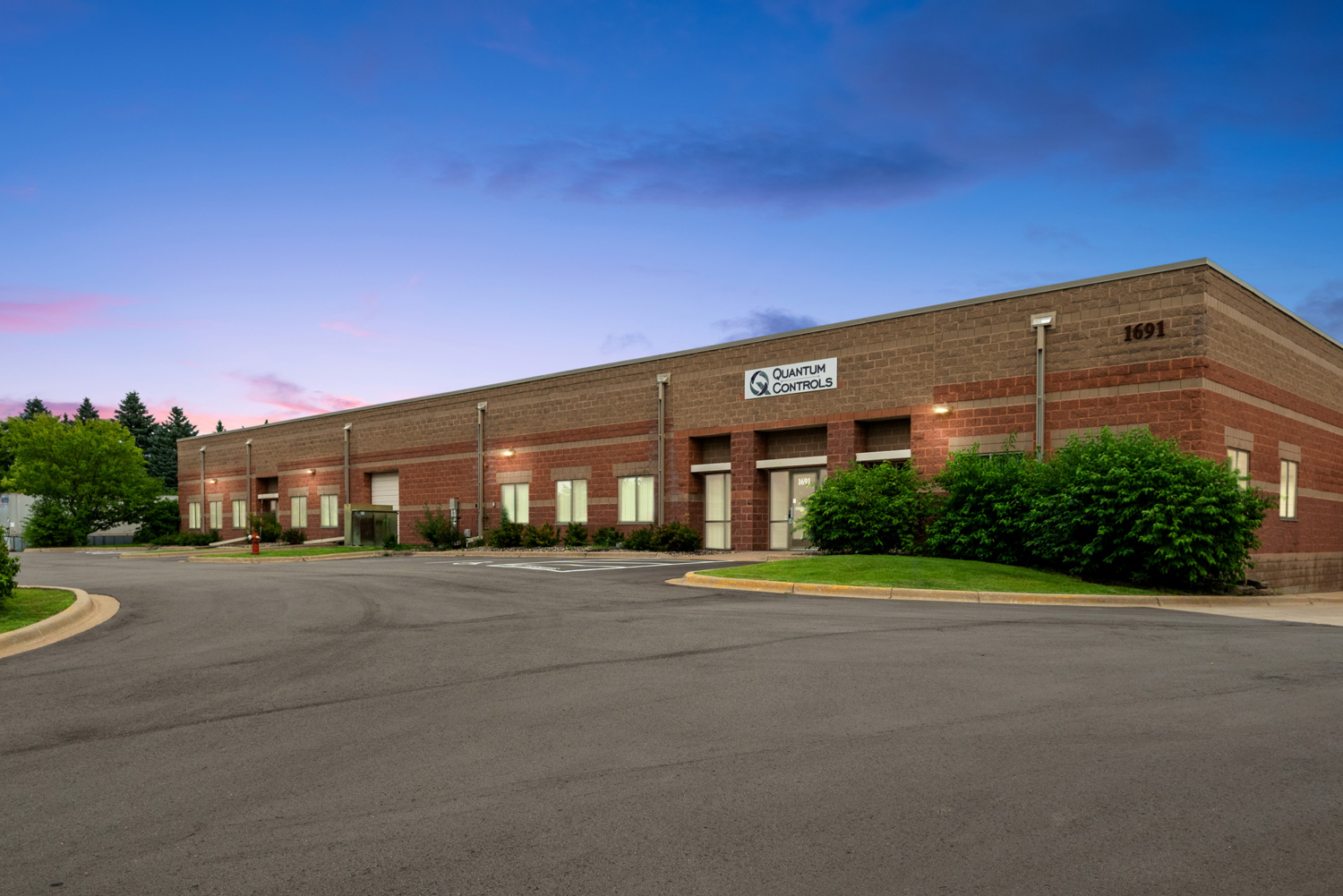 The exterior of the Quantum Controls headquarters and manufacturing facility at twilight, featured alongside the announcement that the company is continuing forward with new ownership and the same commitment to quality.